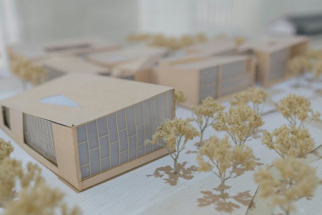 Maquette van een gebouw in karton tussen kleine modelboompjes